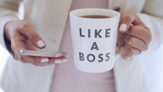 Professional,Woman,Using,Mobile,Phone,And,Holding,A,Cup,That