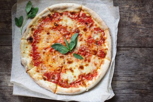 margherita pizza on white tissue paper on a wooden surface