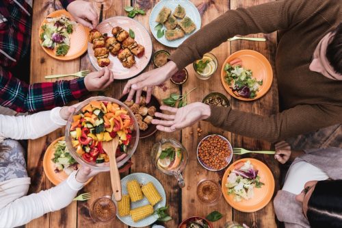 people having dinner together with many foods on the table