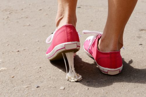 A foot in pink sneakers stuck into chewing gum on street