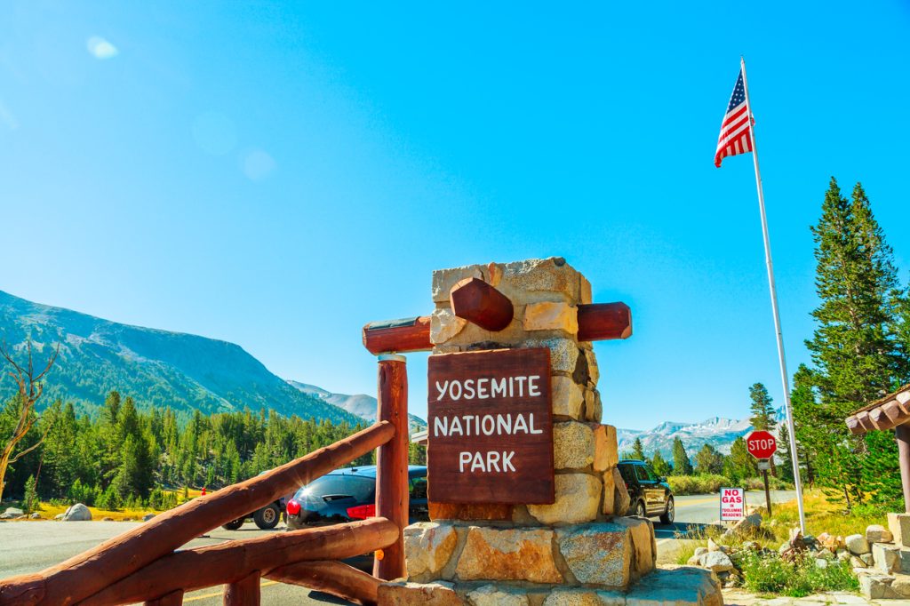 The entrance gate of Yosemite National Park with an American flag in the background