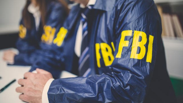 Closeup of two FBI agents sitting in a conference room