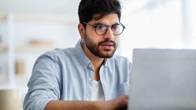 Concentrated male freelancer working on laptop,