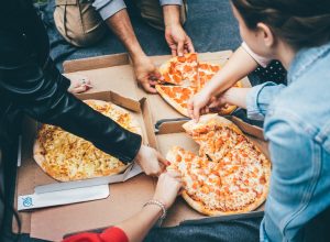 A group of people eating delivery pizza from boxes