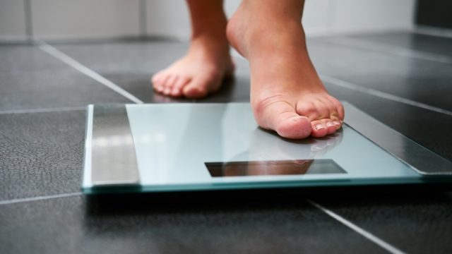 Female bare feet with weight scale in the bathroom