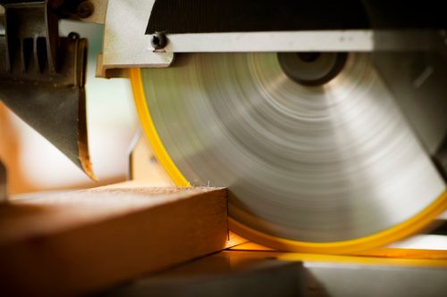Closeup of a circular saw cutting through construction timber. Horizontal shot.