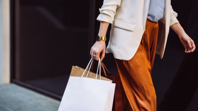 Unrecognizable businesswoman carrying paper bags while walking at the city street.