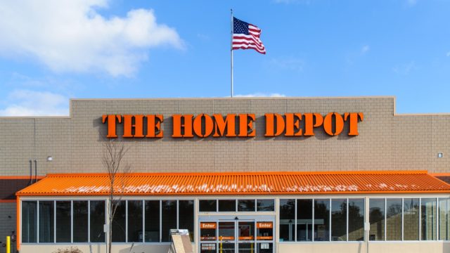 An American flag flies over the entrance and outside facade of a large Home Depot store that sells a full range of building matrerials