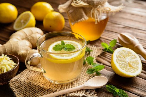 lemon ginger tea surrounded by lemons and ginger on a wood background