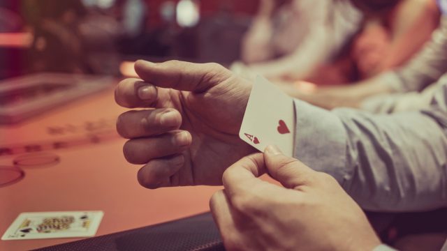 A close up of a person pulling a hidden card out of their sleeve while cheating in a casino