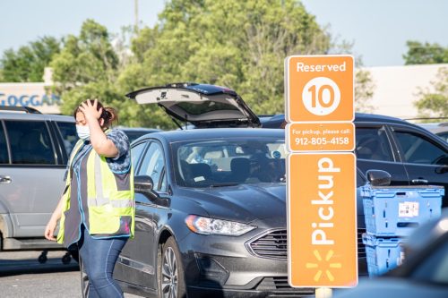 Vidalia, Georgia, USA - May 6, 2021: A Walmart employee loads grocery items to a customer’s vehicle parked at a designated Pick-Up area.