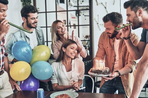 Young woman with friends presenting her a birthday cake.