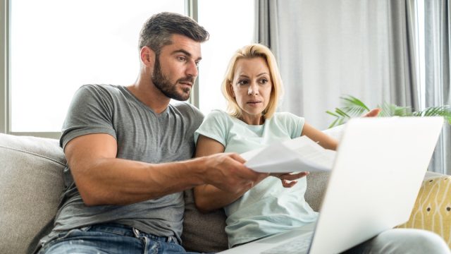 Mid adult couple having problems with home financials. Using laptop and paying bills.