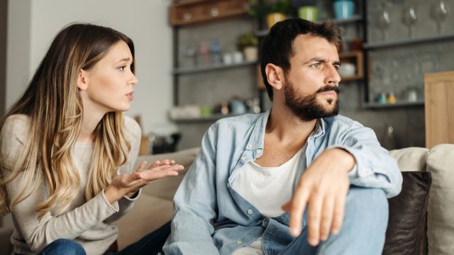 Young woman asking her boyfriend for forgiveness at home