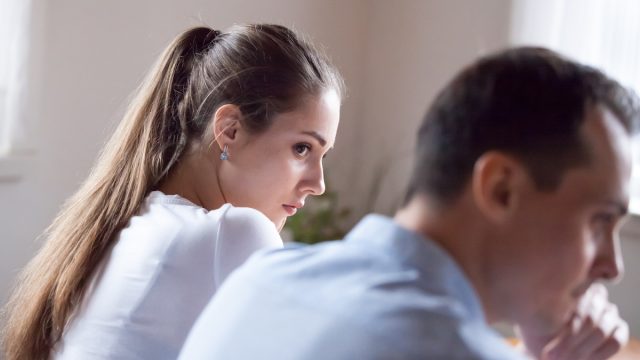 Back view of an offended woman looking at stubborn lover refusing reconcile after a fight