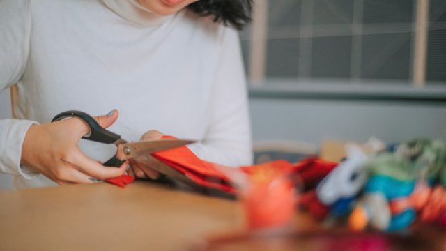 girl cutting fabric preparing cross-stitch craft at home side hustle