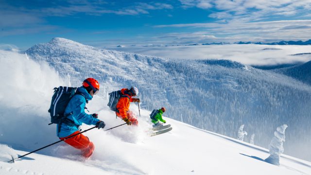 A group of three skiers schussing down a slope