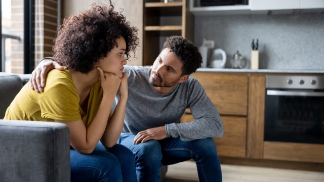 man comforting his girlfriend at home while she is looking upset - lifestyle concepts