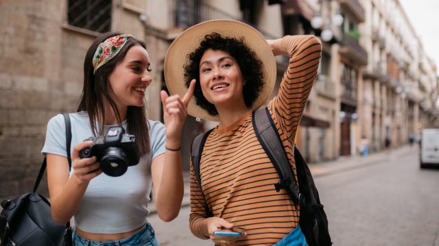 Two women walking down the street with cameras on a trip