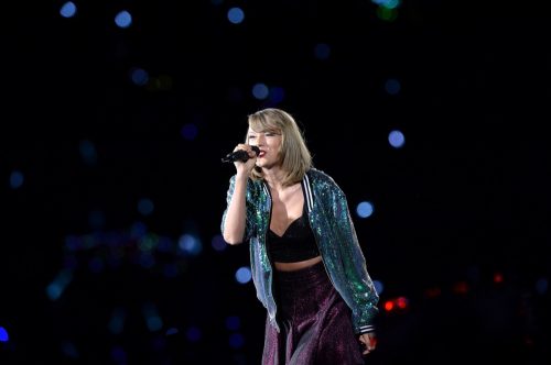 Taylor Swift performs on her 1989 tour wearing a black and sequined outfit.