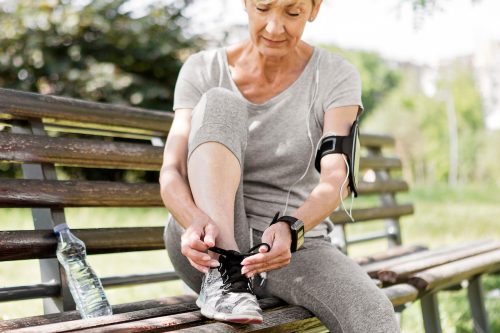 Older woman in athletic wear tying sneaker