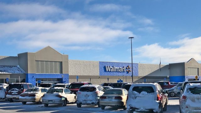 Busy Walmart superstore parking lot on a winter day with blue sky and white clouds.