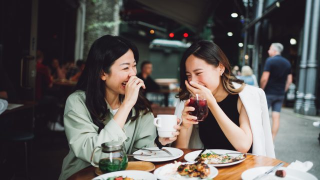 two asian women laughing and eating lunch together