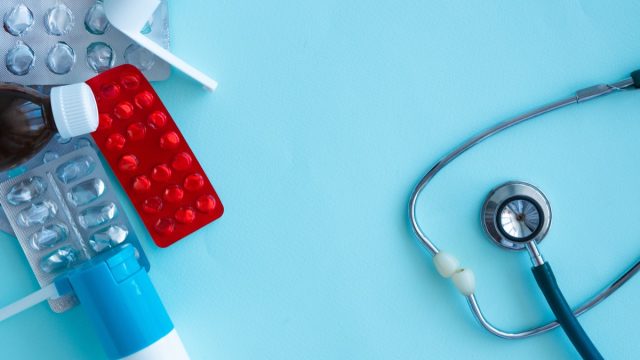 Medicines, empty pill blisters, potion bottles, inhaler and medicinal spray bottles, phonendoscope on blue with space for text. Medicine shortage concept.