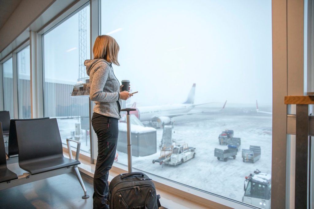 Woman standing close to window with luggage at airport