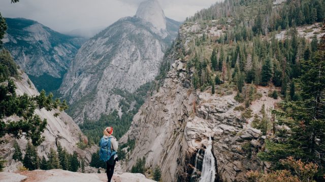 A hiker standing on a peak overlooking Yosemite National Park