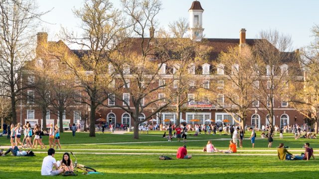 students sit outside of their College building.