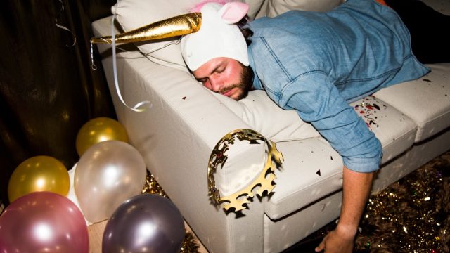 Hungover man on a couch after a party.