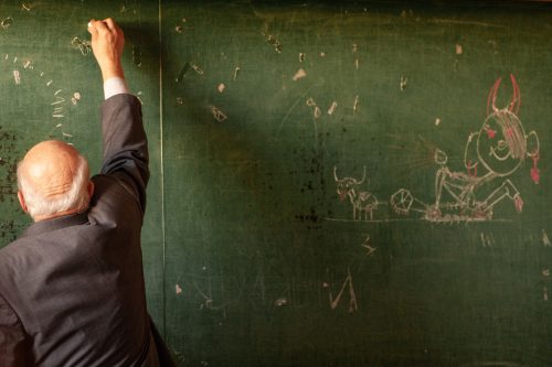 math teacher writing on a chalkboard