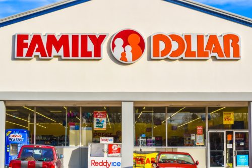 Horizontal, medium closeup of "Family Dollar" chain discount store's exterior facade brand and logo signage in red and orange letters above glass store front.