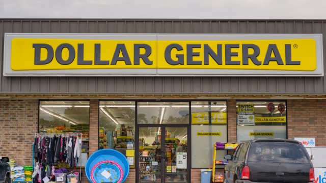 The front of a Dollar General store with a black SUV parked in front.