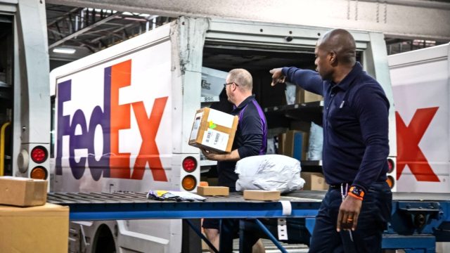 Two FedEx employees sorting packages onto a truck