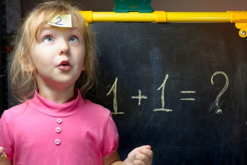 little girl in front of chalkboard with math equation