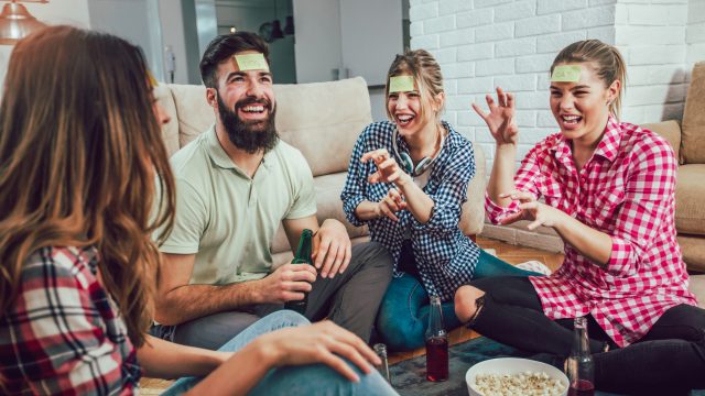 group of friends drinking beer and playing party games at home