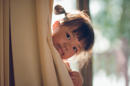 little girl with her had peaking out of the curtain