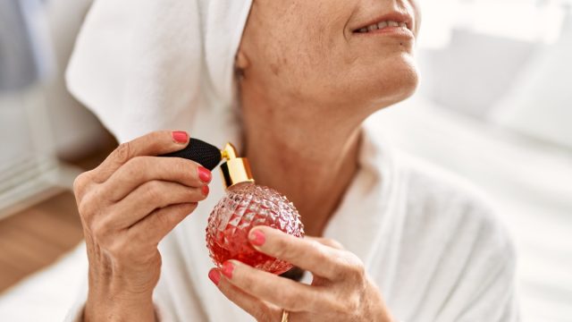 older woman spraying perfume