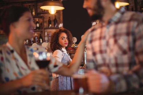 Woman looking jealously at another man and woman from across the bar