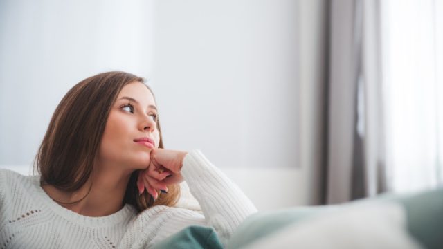 Woman in a white sweater, looking out the window being intuitive.