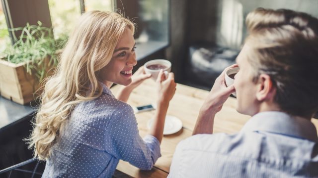 Handsome young man and attractive young woman are spending time together. Romantic couple in cafe is drinking coffee and enjoying being together.