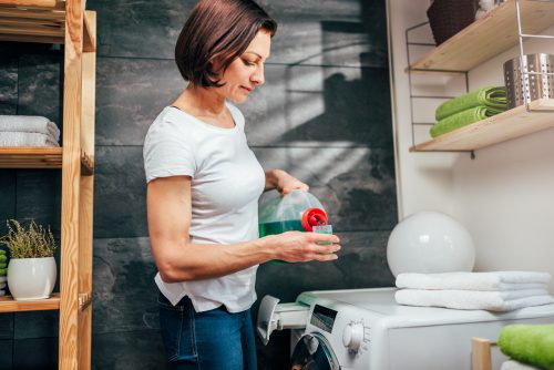 A woman measuring laundry detergent in the cap to pour into a washing machine
