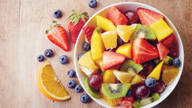 A bowl of fruit with oranges, strawberries and blueberries.