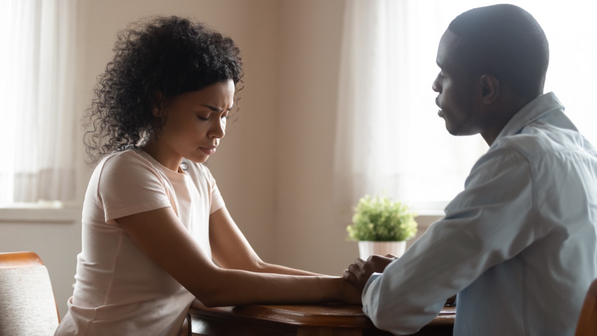Couple holding hands at a table having a serious conversation.