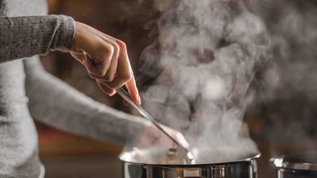 Closeup of someone stirring a pot of soup on the stove