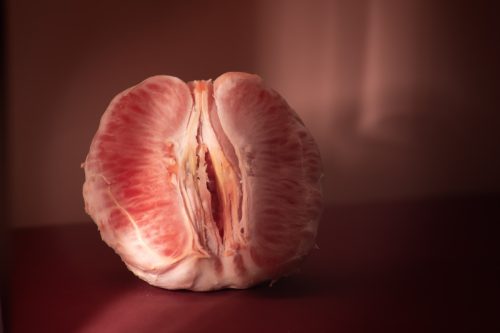 Peeled grapefruit divided in half on a red table