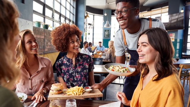 Group of friends smiling at waiter in restaurant