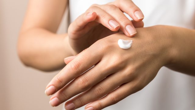 Woman putting moisturizer on her hand.